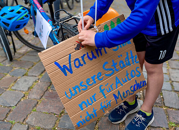 Demoschild auf dem steht: Warum sind unsere Städte nur für Autos nicht für Menschen