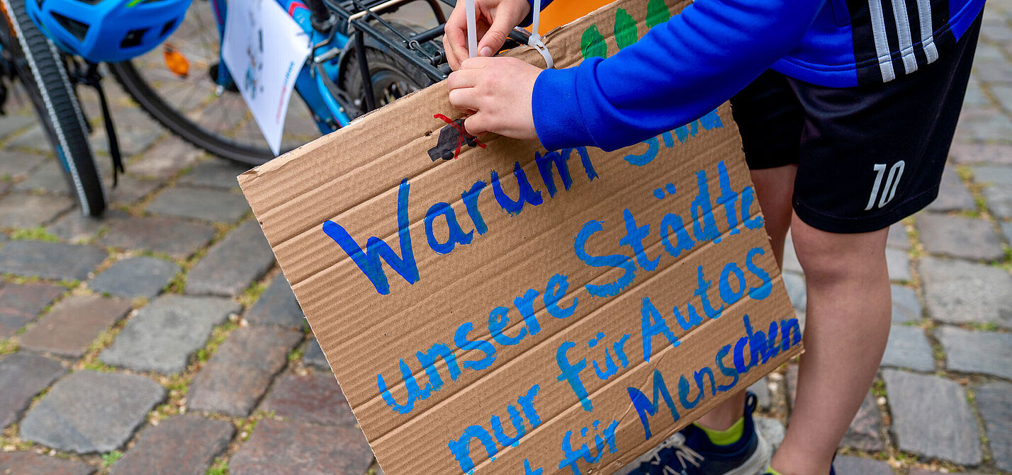 Demoschild auf dem steht: Warum sind unsere Städte nur für Autos nicht für Menschen