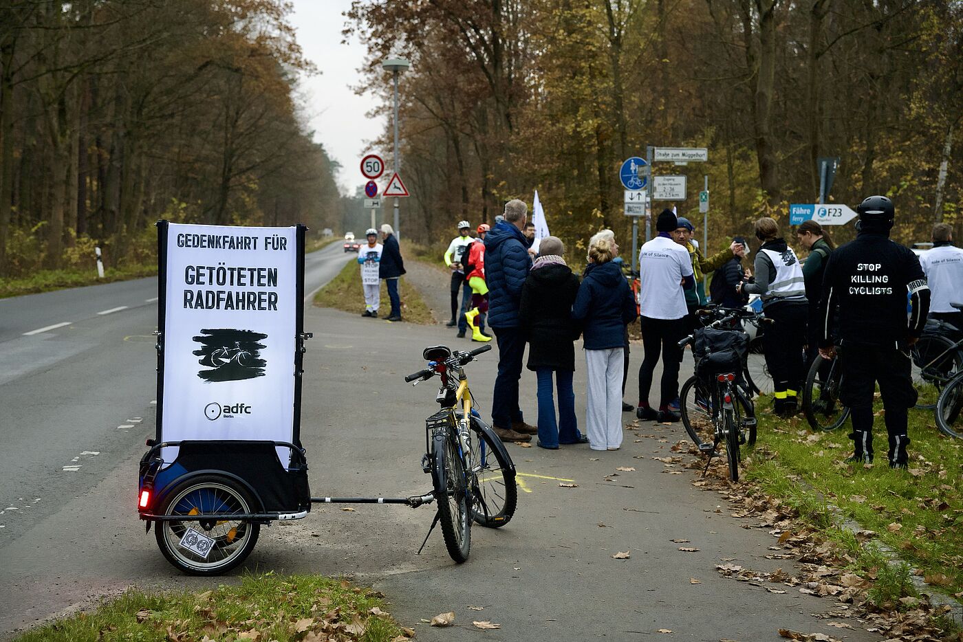 Menschen stehen für eine Mahnwache auf der Straße, Vision Zero Transparent im Vordergrund