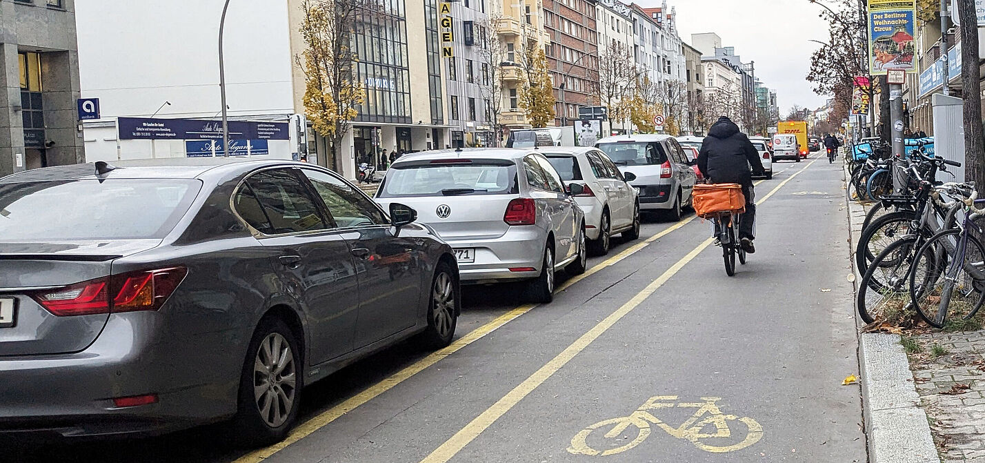 Radweg der links durch parkende Autos abgegrenzt wird