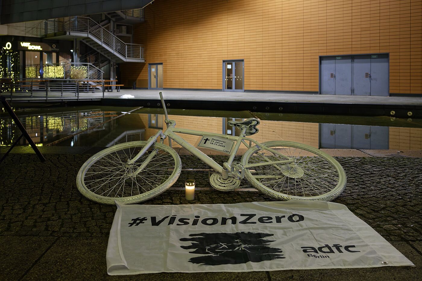 Ein weißes Geisterrad liegt hinter einer weißen Vision Zero Fahne