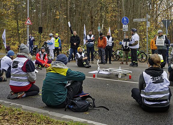 Menschen sitzen zur Mahnwache auf der Fahrbahn und gedenken eines getöteten Radfahrers