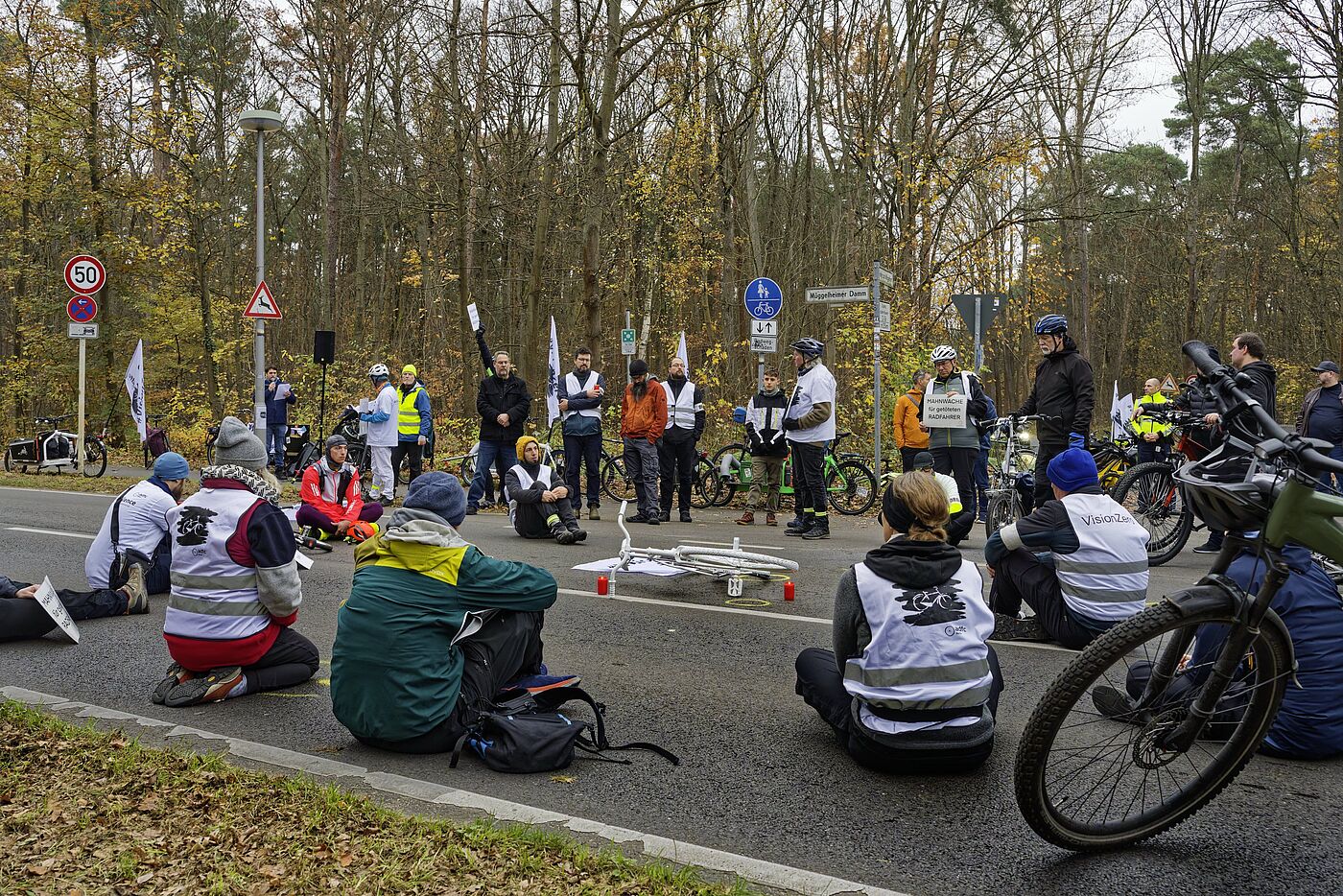 Menschen sitzen zur Mahnwache auf der Fahrbahn und gedenken eines getöteten Radfahrers