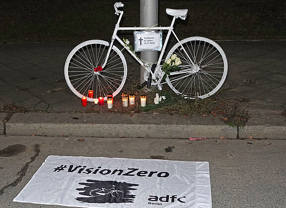 Ein weißes Geisterrad davor eine weiße Vision Zero Fahne