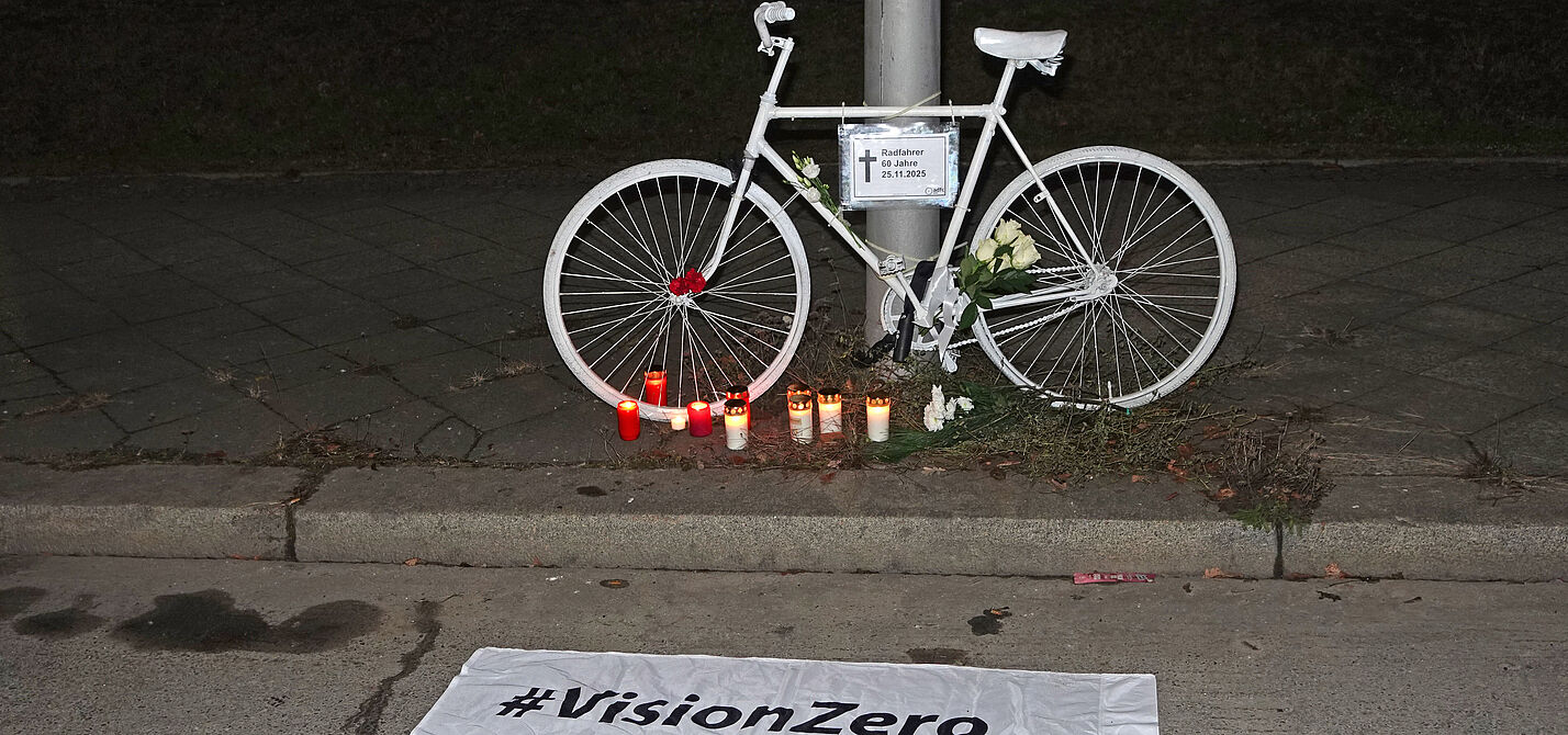 Ein weißes Geisterrad davor eine weiße Vision Zero Fahne